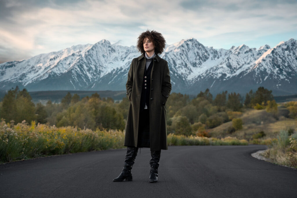 Young women wearing loden coat in front of snowy mountains